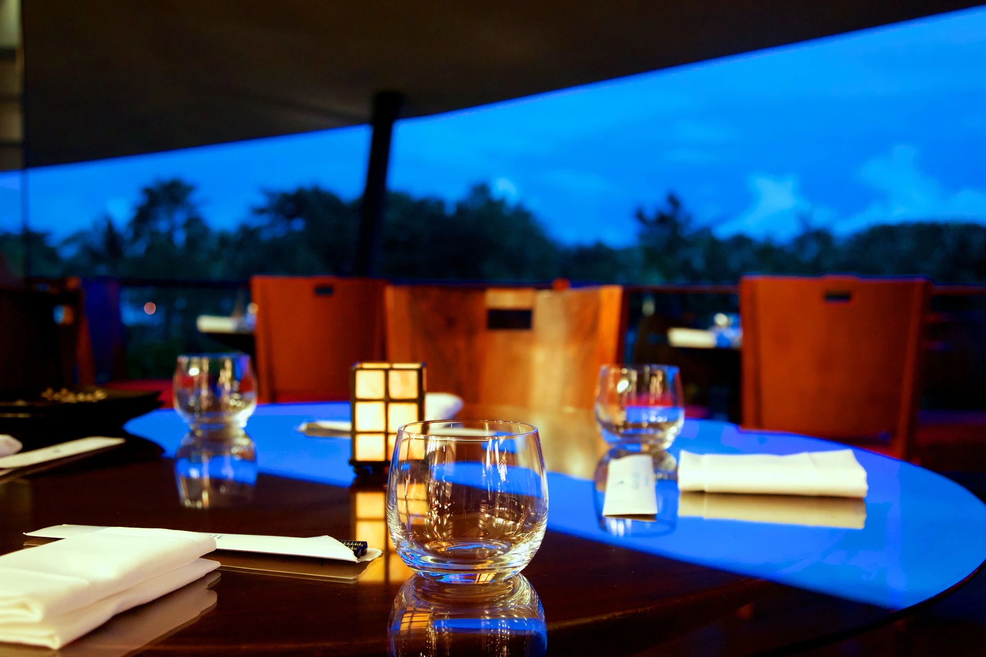 A glass on a set table outdoors at dusk
