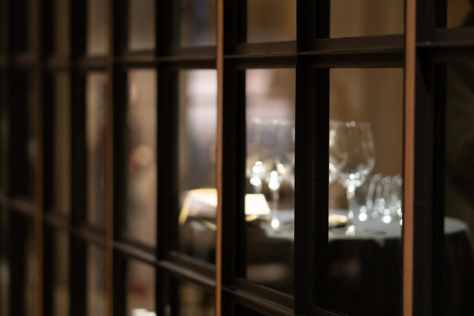 A softly lit dining room seen through a paned glass door